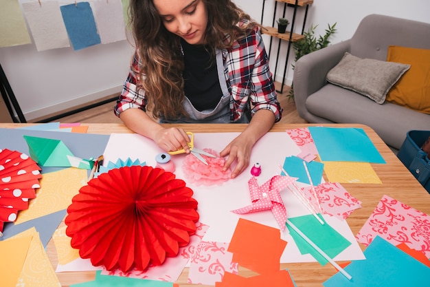 Close-up of young woman making beautiful flower craft at home