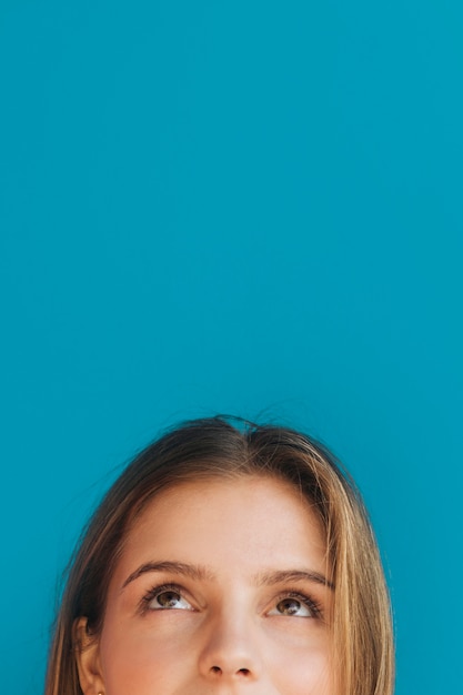 Close-up of young woman's face looking up against blue backdrop