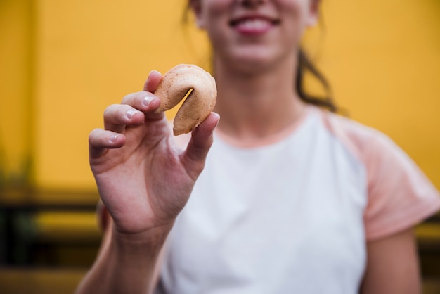 Close-up of a young woman showing fortune cookie in front of camera
