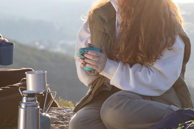 山の頂上に茶碗と座っている若い女性のクローズアップ