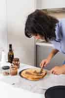 Free photo close-up of a young woman spreading the peanut butter on pancake with knife and spoon