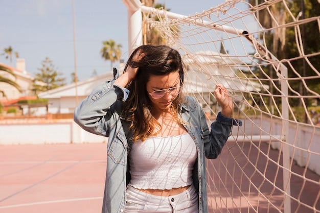 Foto gratuita primo piano di una giovane donna in piedi vicino alla rete di calcio