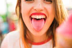 Free photo close-up of a young woman sticking out tongue