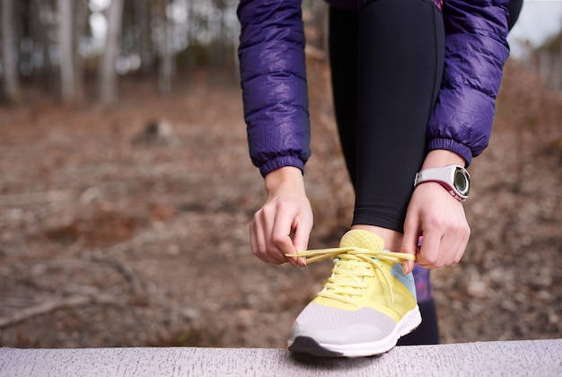 Close up on young woman tying her shoe