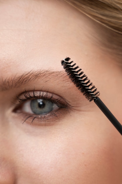 Free photo close-up of young woman using mascara