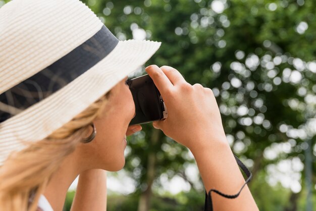 カメラから写真を撮る帽子をかぶっている若い女性のクローズアップ