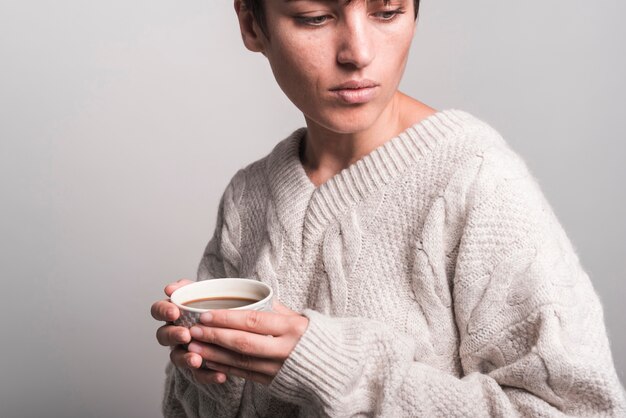 Крупным планом молодая женщина, носить свитер, проведение кофейной чашки