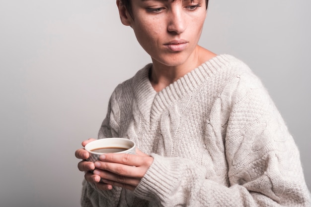 Close-up of young woman wearing sweater holding coffee cup