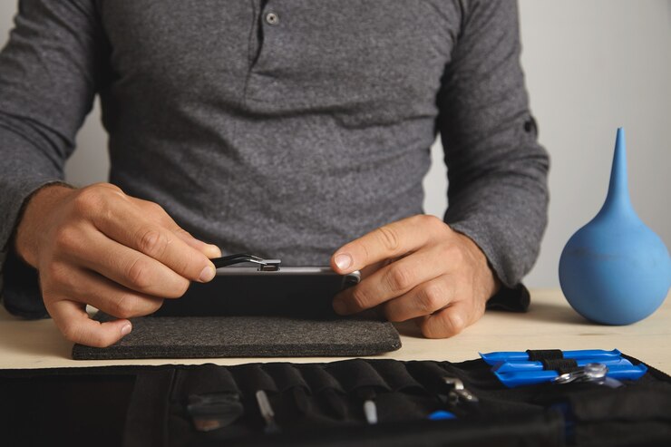 Free Photo close view, master uses pincher tool to remove sim card slot from smart phone while disassembling it