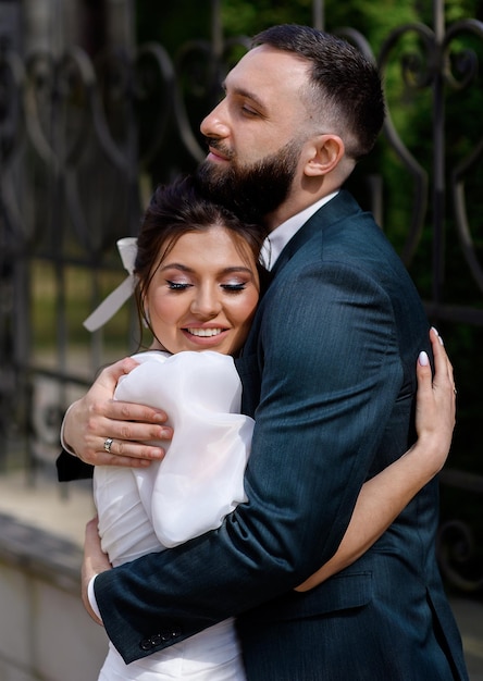 Free photo close view of two adults man and woman dressing in stylish clothes hugging each other during walk outdoor beautiful girl with makeup closing eyes and smiling while embracing her boyfriend in street