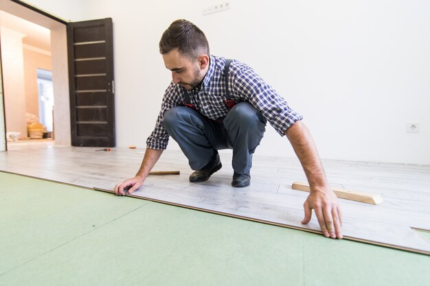 Close view of Young worker laying a floor with laminated flooring boards
