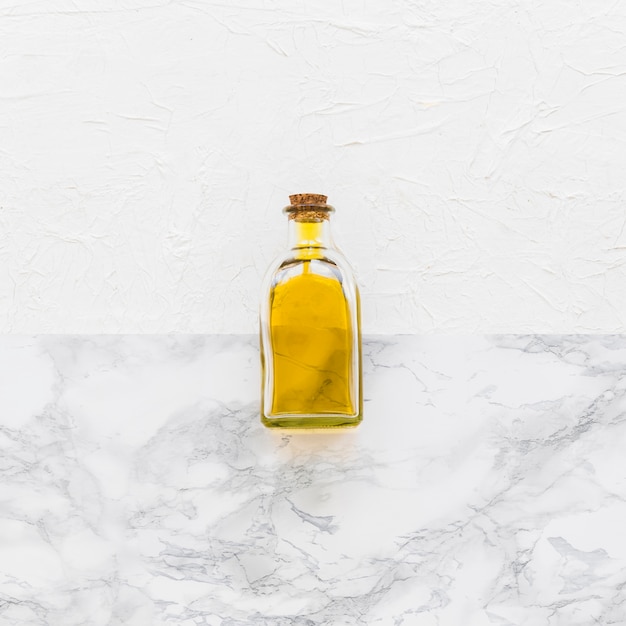 Closed glass oil bottle on two textured backdrop