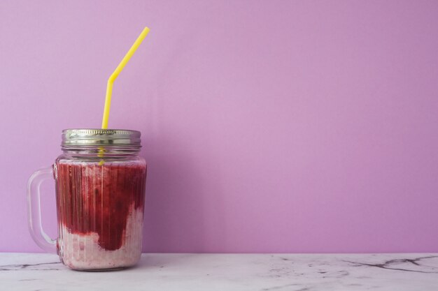 Closed smoothies in the jar with yellow straw