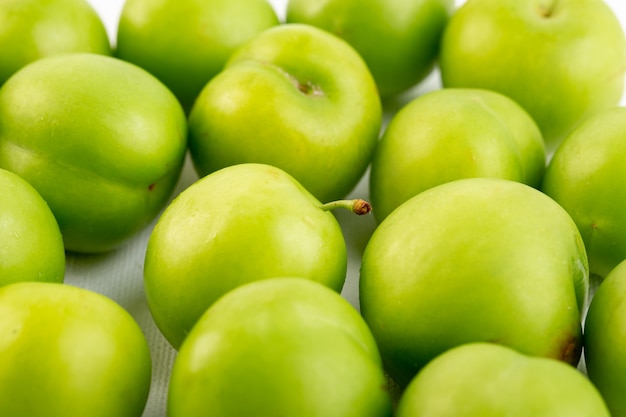 Закрытый вид сверху зеленая вишня-слива круглый изолированный кислый свежий спелых на белом фоне качества фруктов