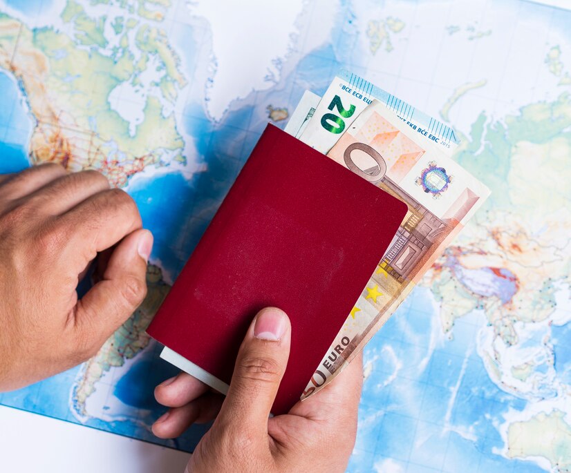 Hands holding a red passport with euro banknotes inside, placed over a colorful world map background.