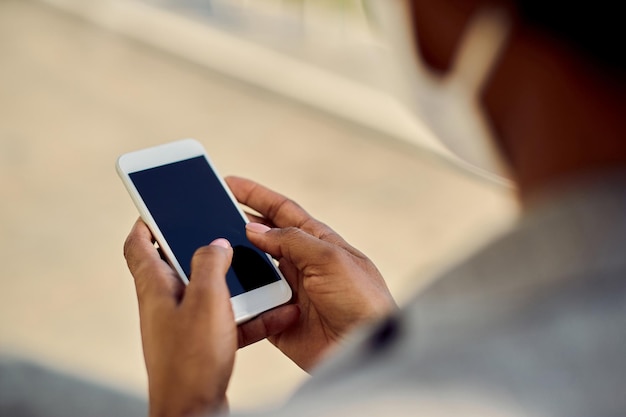 Closeup of African American businesswoman texting on cell phone outdoors