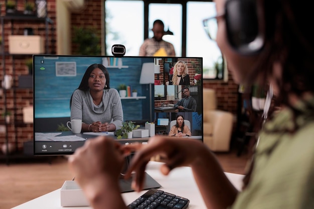 Free photo closeup of african american freelancer with wireless headphones in online interview with startup owner and human resources team. woman in video call conference working remote from home.