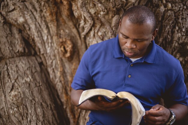 나무와 성경을 읽고 아프리카 계 미국인 남자의 근접 촬영