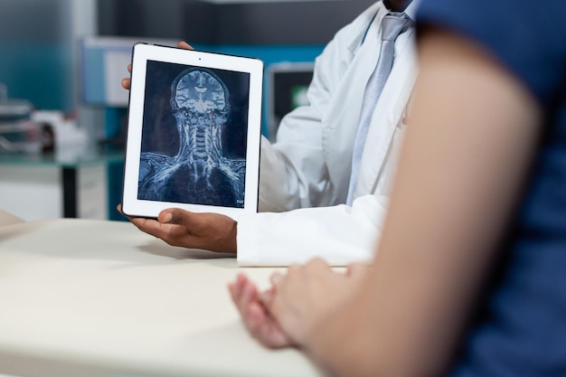 Closeup of african american radiologist holding tablet with bones radiography