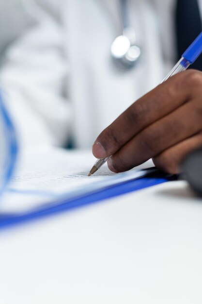 Closeup of african american specialist doctor hand analyzing sickness expertise writing medical treatment on clipboard Therapist man working at medicine prescription in hospital office