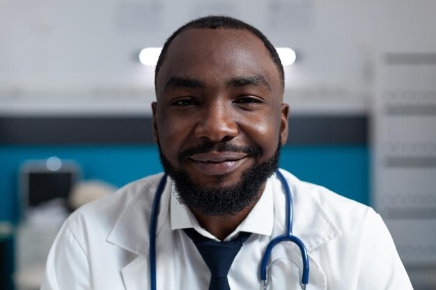 병원 사무실에서 치료를 하는 청진기를 가진 아프리카계 미국인 전문 의사의 클로즈업. 약 처방 보고서를 분석하는 개업의 남자. 의료 서비스