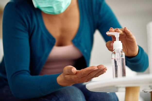 Closeup of African American woman cleaning her hands with antibacterial gel at home