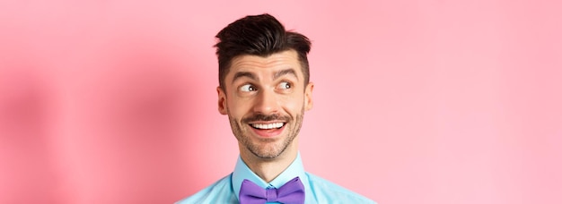 Free photo closeup of amused smiling guy with moustache pointing and looking left happy stare at logo standing