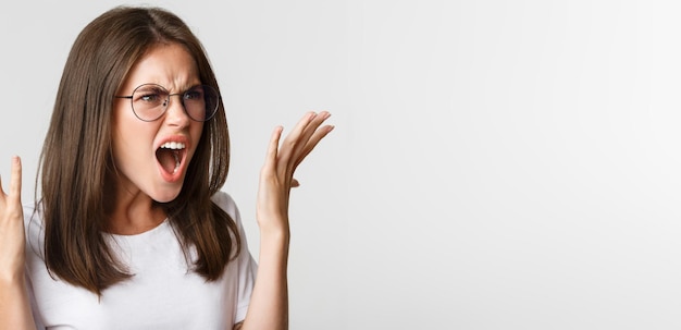 Foto gratuita primo piano di una bella donna arrabbiata e indignata con gli occhiali che urla e stringe la mano con un argomento