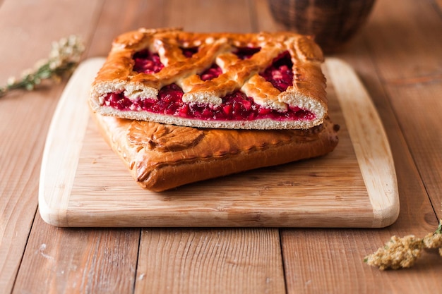 Closeup of appetizing typical Russian stuffed sweet berry pie on a wooden cutting board