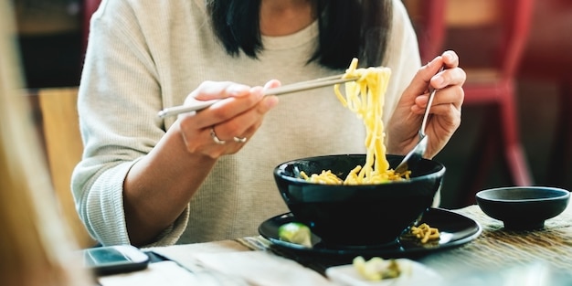 Макрофотография азиатской женщины едят лапшу