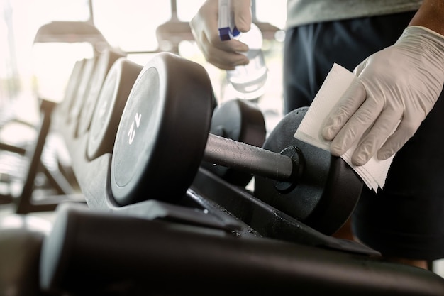 Closeup of athlete disinfecting hand weights in a gym