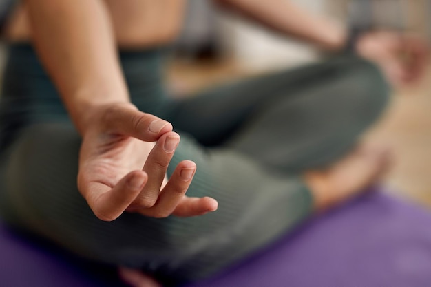 Closeup of athletic woman meditating in lotus position at home