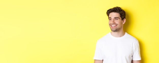 Closeup of attractive bearded man in white tshirt smiling looking left at copy space standing agains