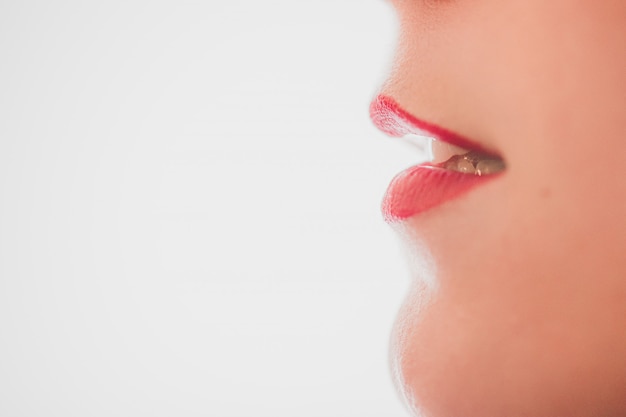 Closeup of attractive lips of a female with lipstick on a white background with space for text