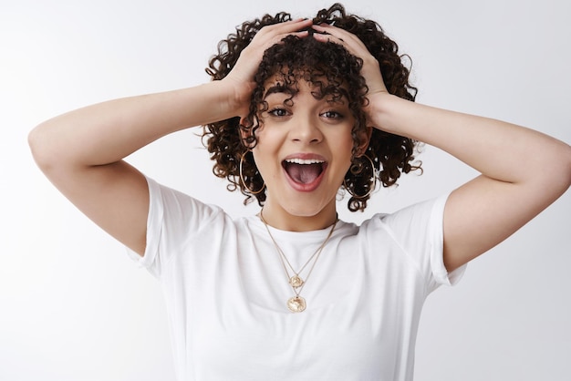 Free photo closeup attractive surprised young happy cheerful curlyhaired girl open mouth excited grab head hands impressed win achieve success cannot believe receive perfect score look amazed white background