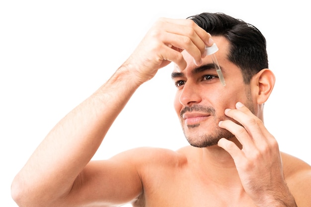 Closeup of a attractive young man in his 20s applying a drop of apply facial serum