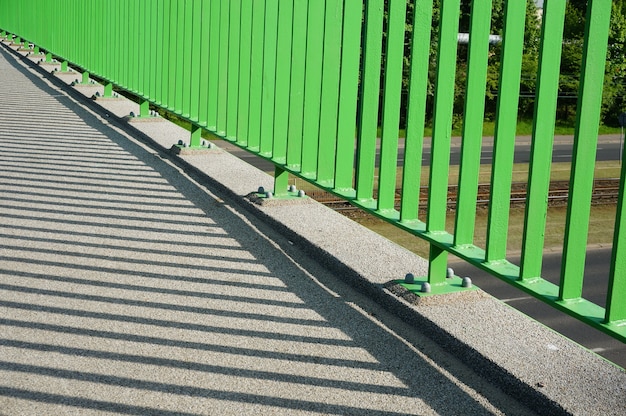 Closeup of the base of the green barrier of an overpass bridge