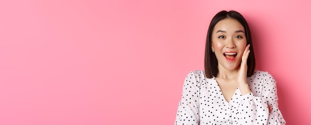 Free photo closeup of beautiful asian woman calling for you making announcement or yelling standing over pink b