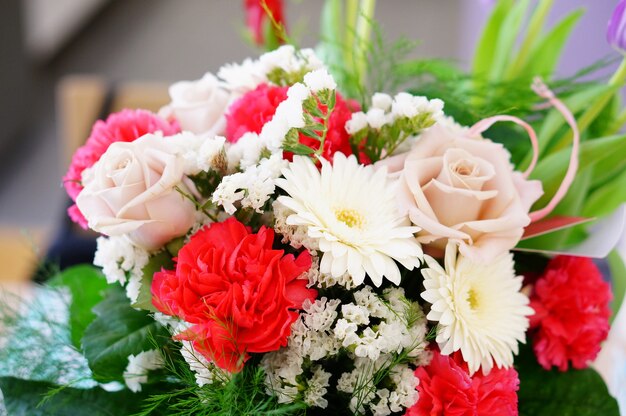 Крупным планом красивый букет цветов, состоящий из роз, статицы, гвоздики и ромашек