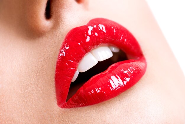 Крупным планом красивые женские губы с красной помадой. Гламурный модный яркий глянцевый макияж.