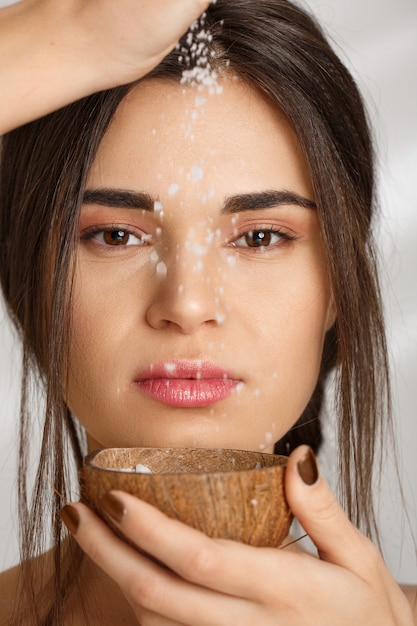 Closeup of beautiful woman pouring salt scrub