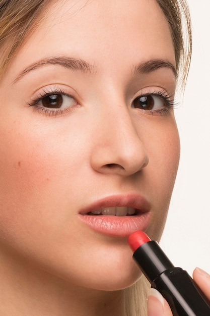 Closeup beautiful woman putting on lipstick 