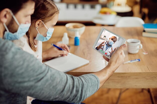 Closeup of black doctor having video call with father and daughter due to coronavirus pandemic