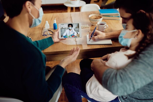 Closeup of black female doctor having video call with a family during coronavirus pandemic