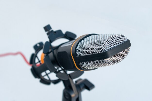 Closeup of a black and grey microphone on a white surface and background