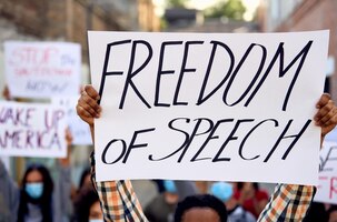 Free photo closeup of black man protesting with large group of people and holding a placard with freedom of speech inscription