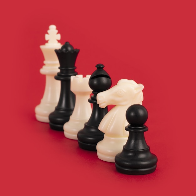 Primo piano dei pezzi degli scacchi in bianco e nero allineati su un rosso brillante