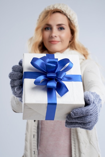 Closeup of blond woman presenting the gift box for Christmas stretching it to camera