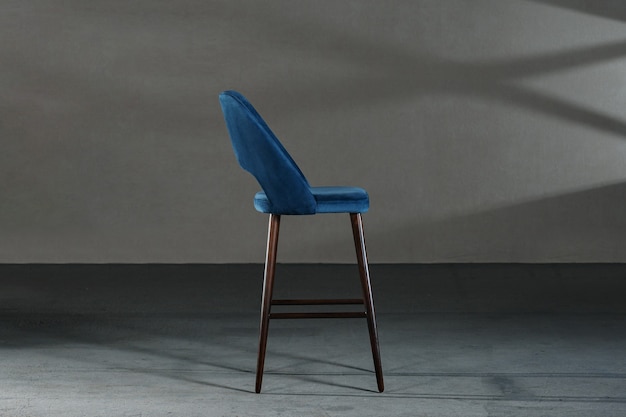 Free photo closeup of a blue chair with high legs in a room with gray walls