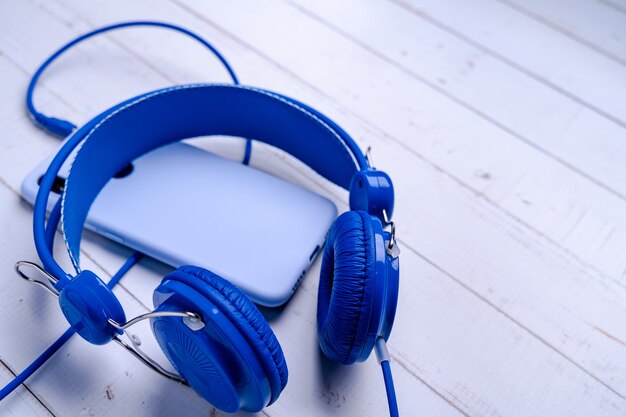 Closeup of blue headphones connected to a phone on a wooden surface